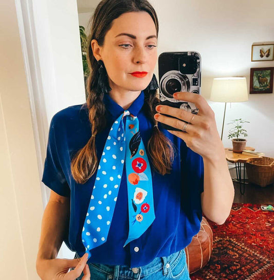 Neck scarf in light blue with cartoon faces, animals and white dot accents