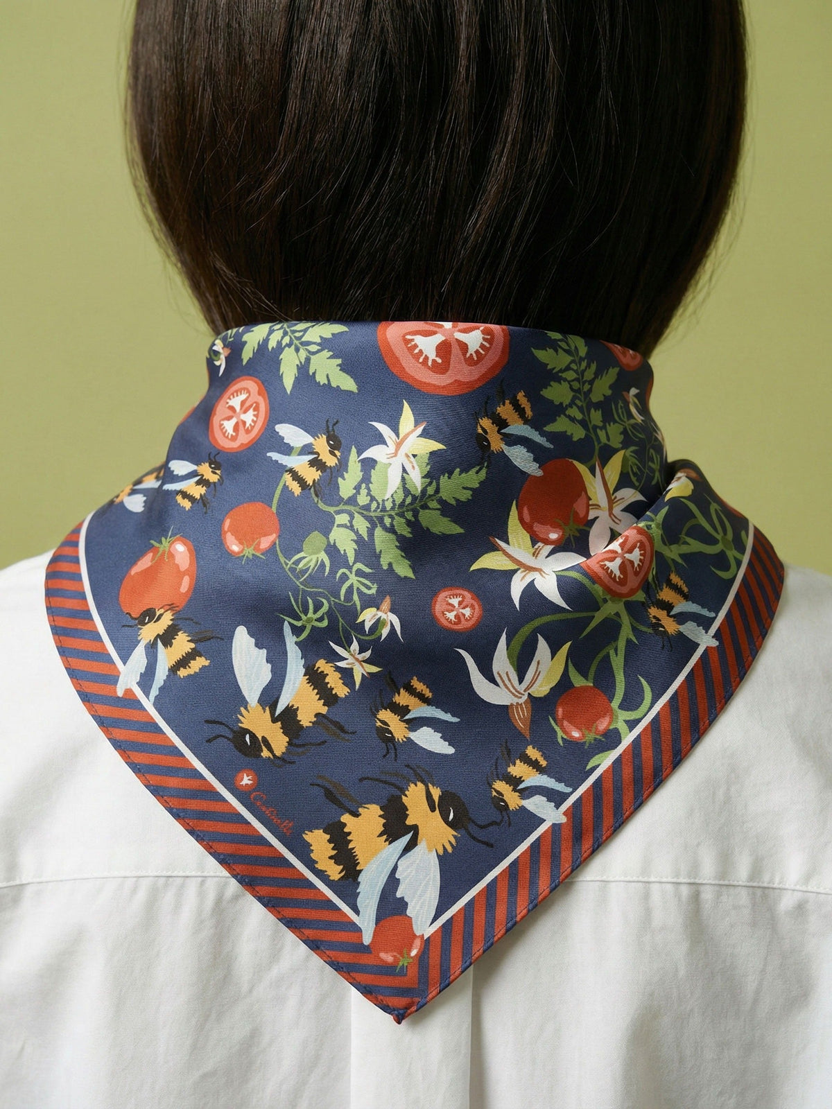 Cotton silk bandana tied at neck, navy print with orange striped edge and flowers