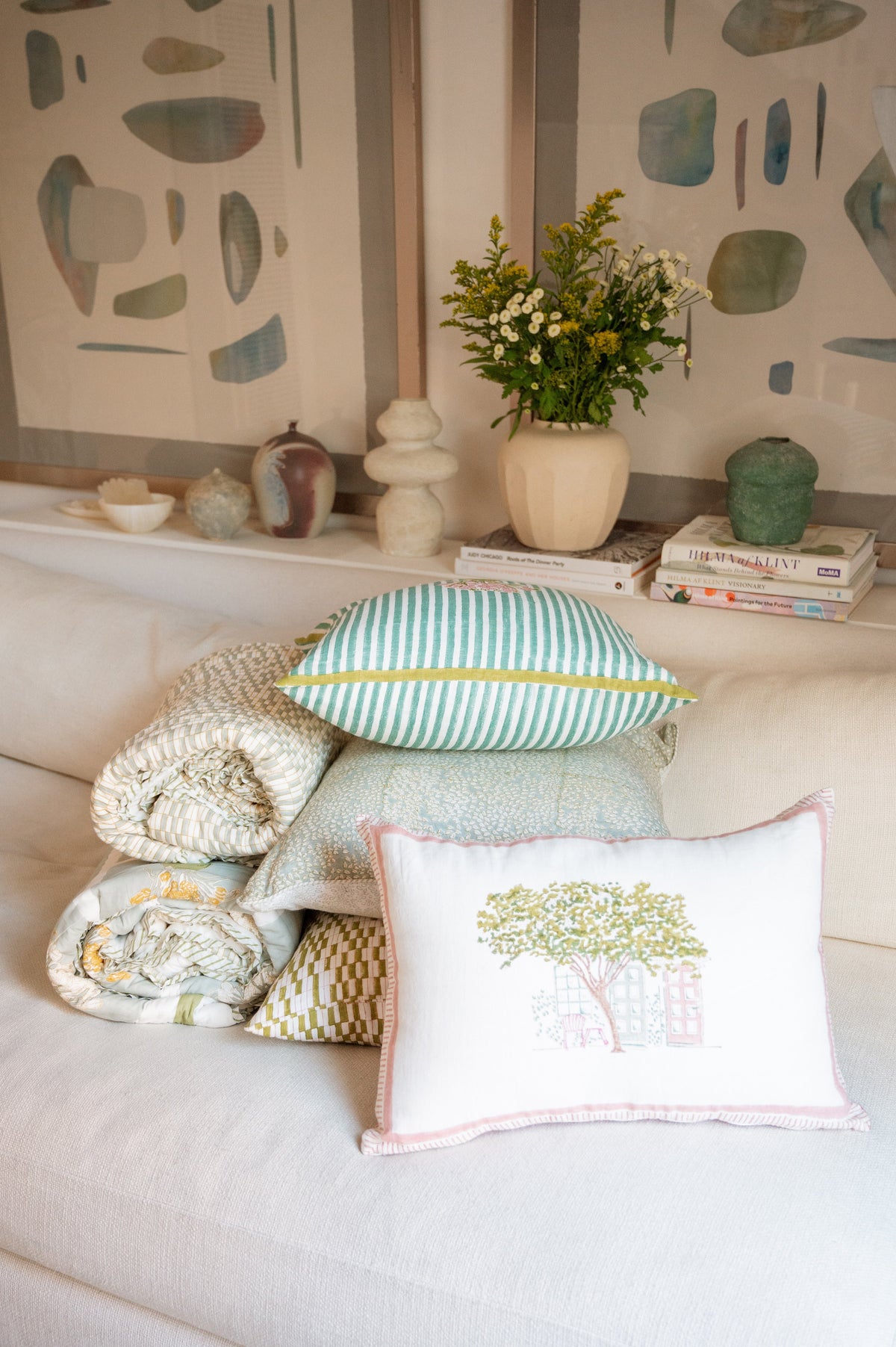 Block print cushion with tree-and-house print and pink trim on sofa, with striped pillow