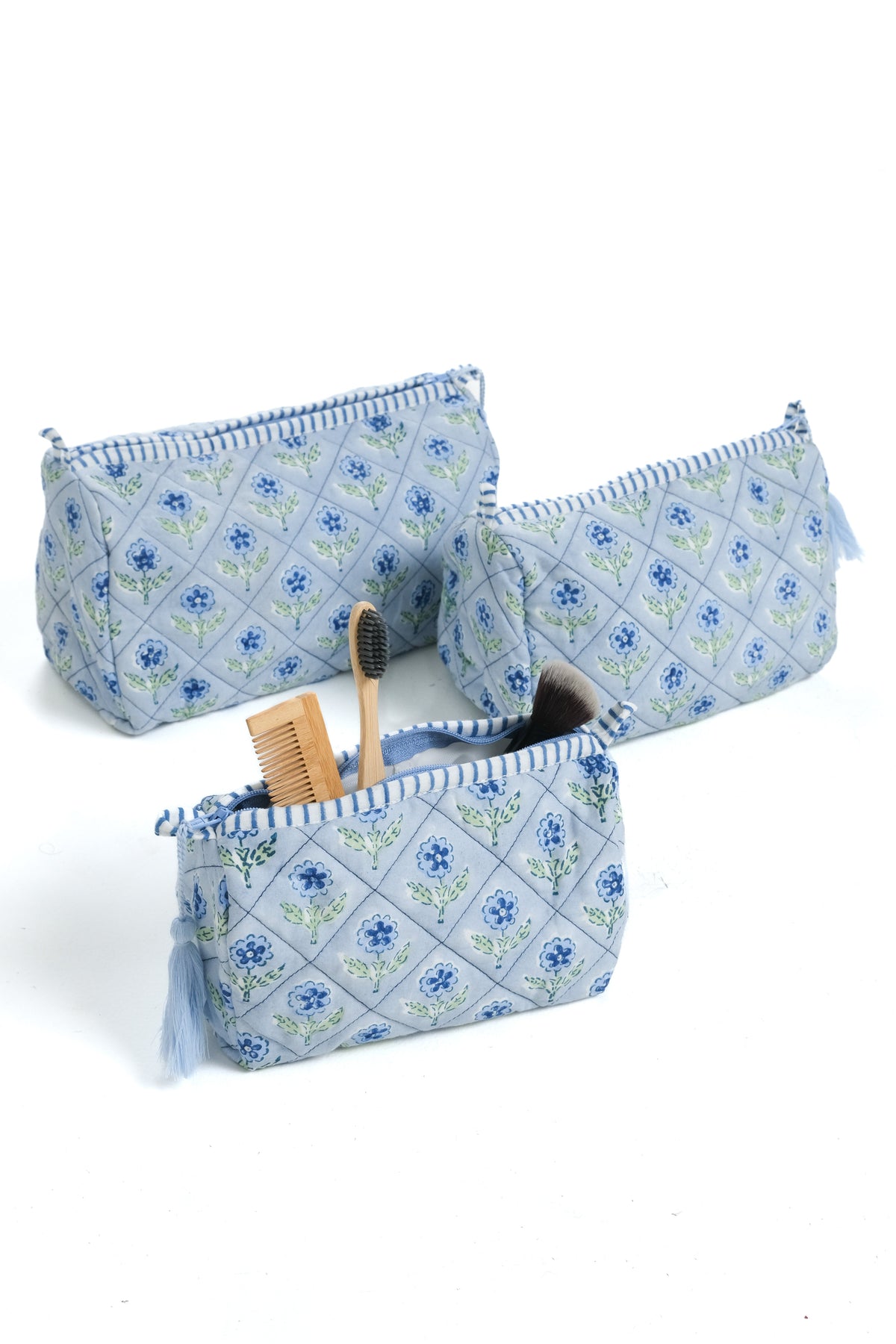Blue blockprint zip makeup bags with tassel trim, shown with brush and comb