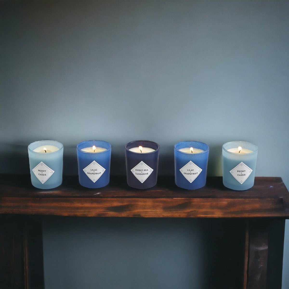 Mediterranean candle gift set with five blue and teal candles on a wooden ledge