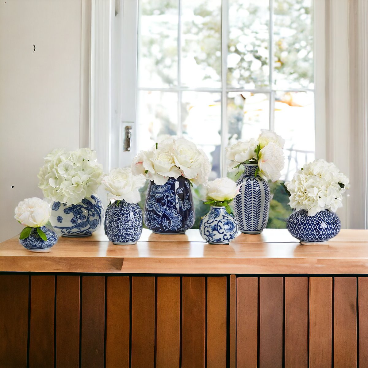 Blue-and-white ceramic vases holding white flowers on a wooden ledge