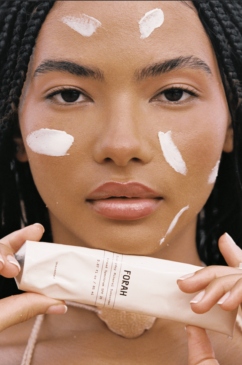 Mineral sunscreen on face with white patches; holding sunscreen tube