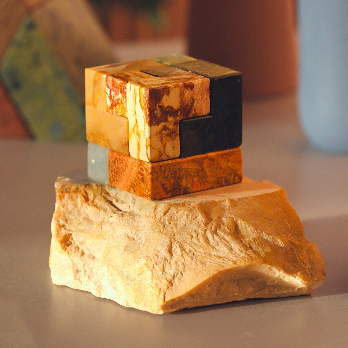 Stacked gemstone cube puzzle on a cut stone base, showing dark and orange blocks.
