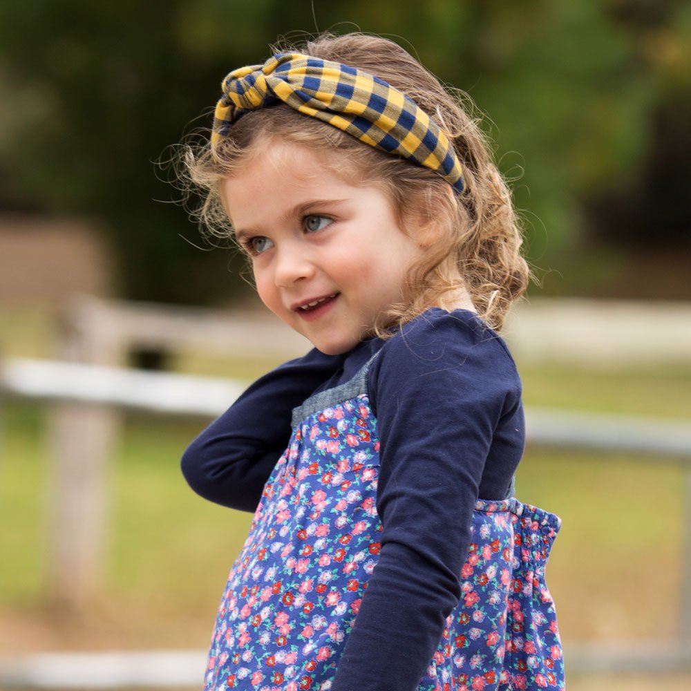 Mustard and navy plaid headband with a twisted front worn by a child