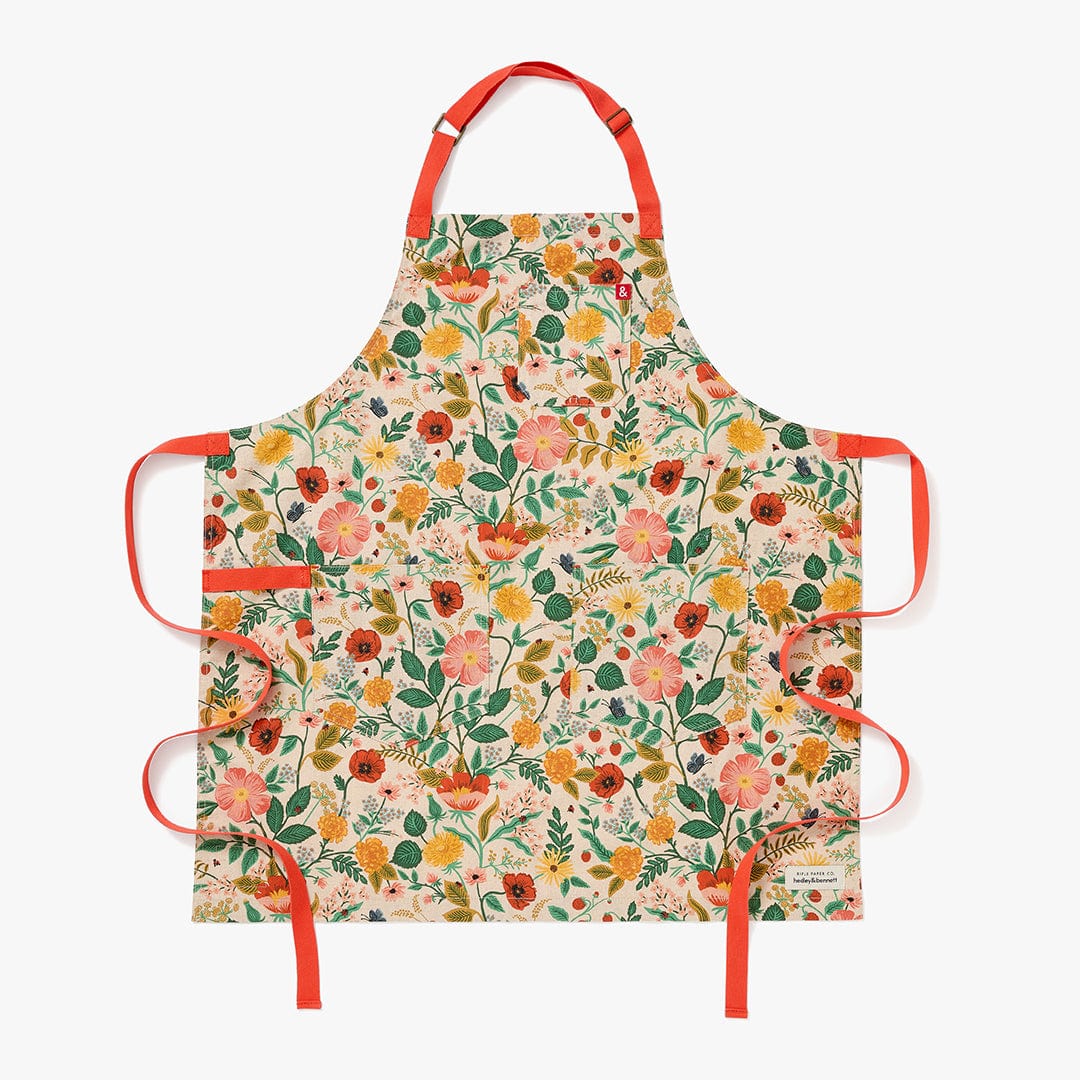 Floral canvas apron with orange straps and side ties, cream background