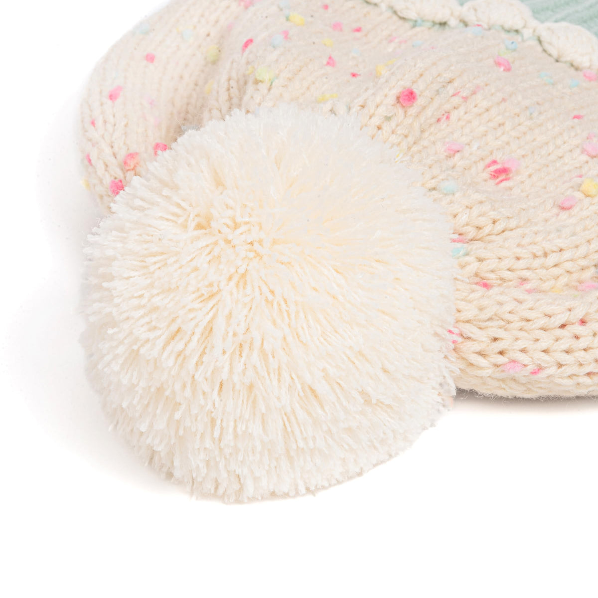 Cream knit beanie detail with large pom-pom and colorful flecks.