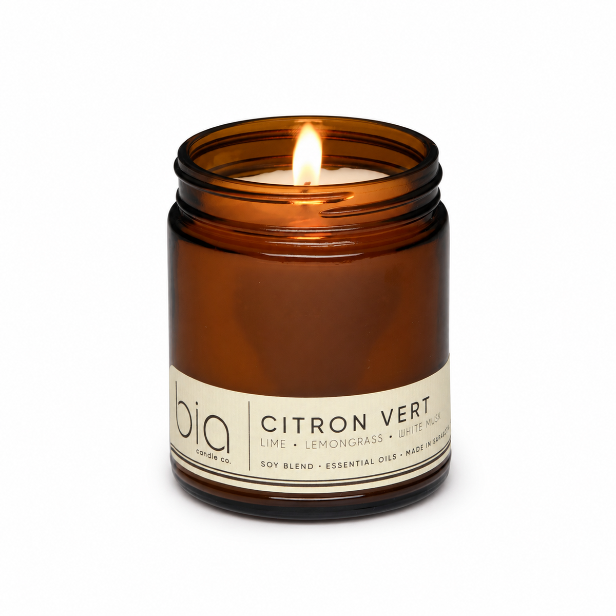 Amber glass soy blend candle with flame, front label and dark ridged jar base