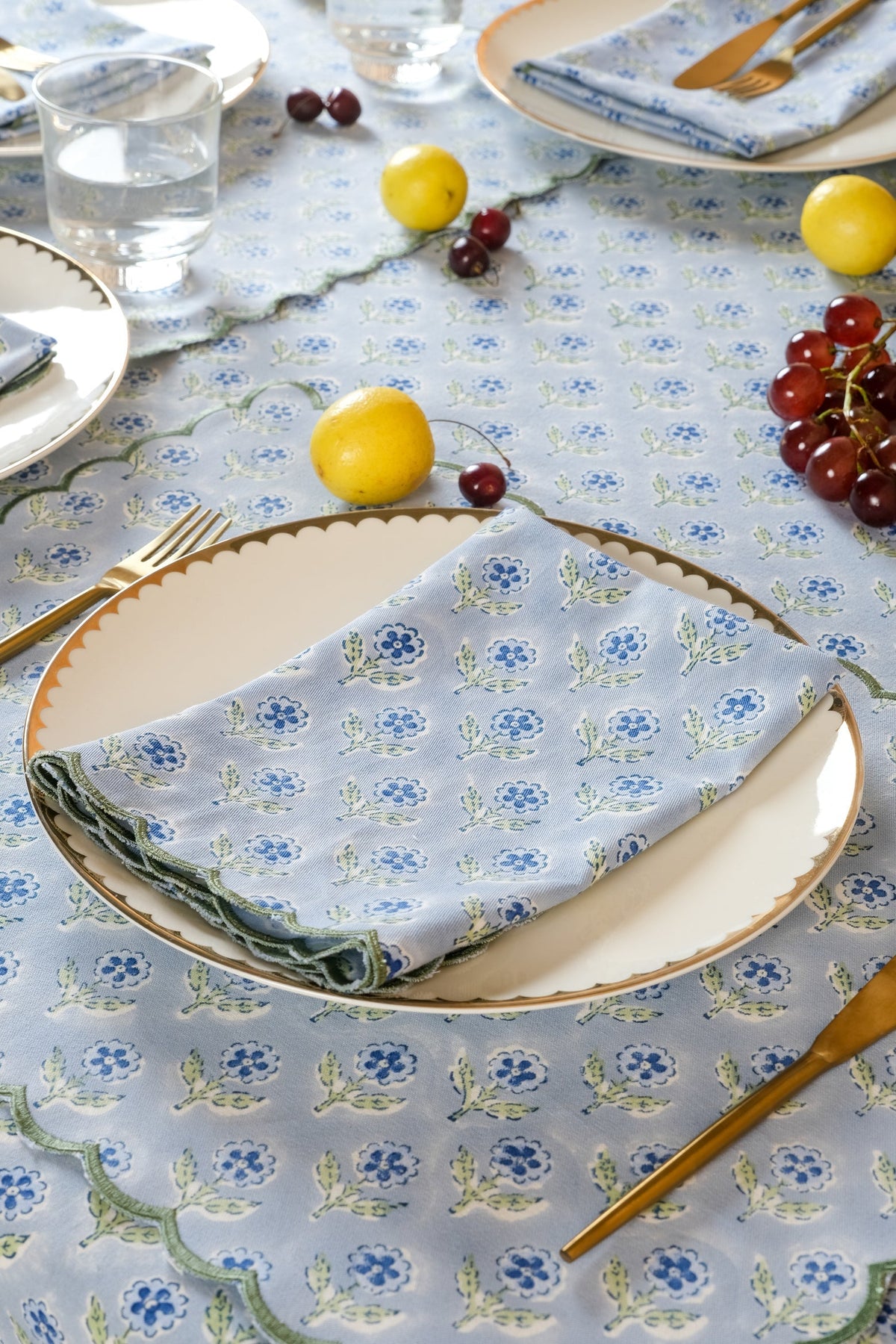 Folded blue scallop-edge napkins with repeating embroidered floral blockprint pattern