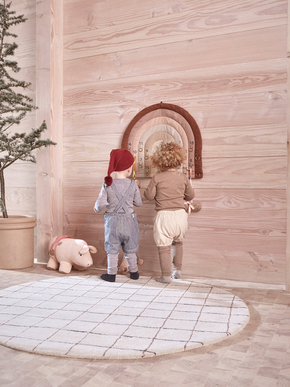 Rainbow arch advent calendar on a wooden wall with numbered hanging ornaments