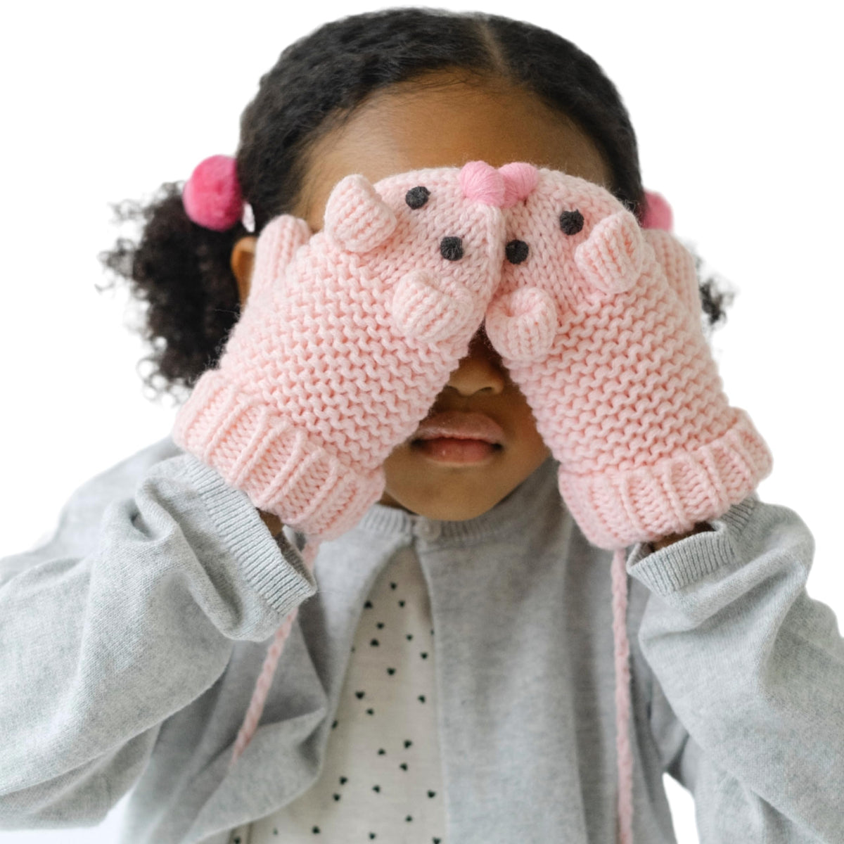 Pink mouse-face knit mittens worn by a child covering their eyes