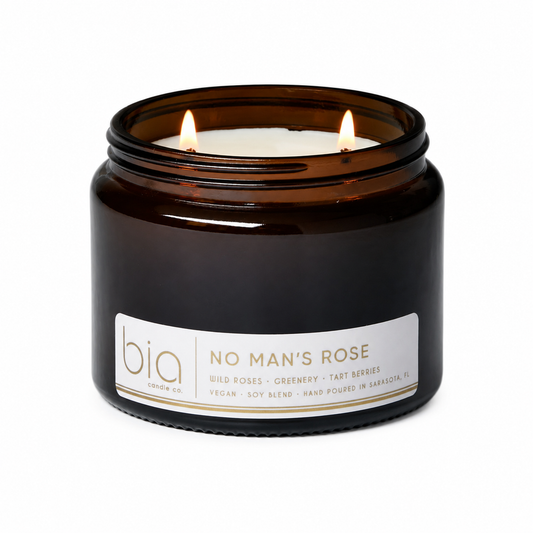 Amber glass soy blend candle jar with lit wick and printed label