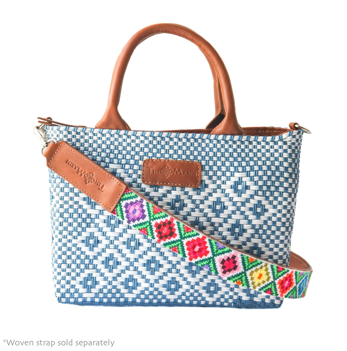 Woven crossbody bag with blue-and-white weave, tan leather handles, and colorful embroidered strap