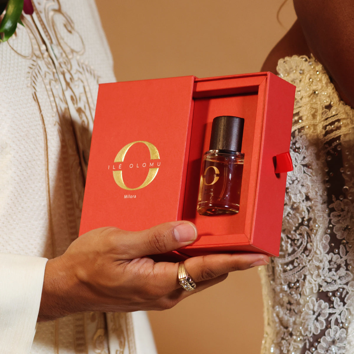 Eau de parfum bottle in open red gift box, dark wooden cap visible