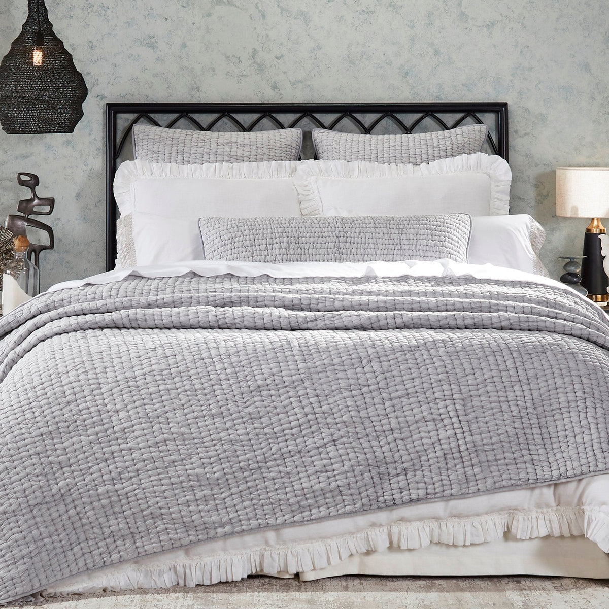 Light gray stone-washed cotton quilt with textured weave, draped across bed.