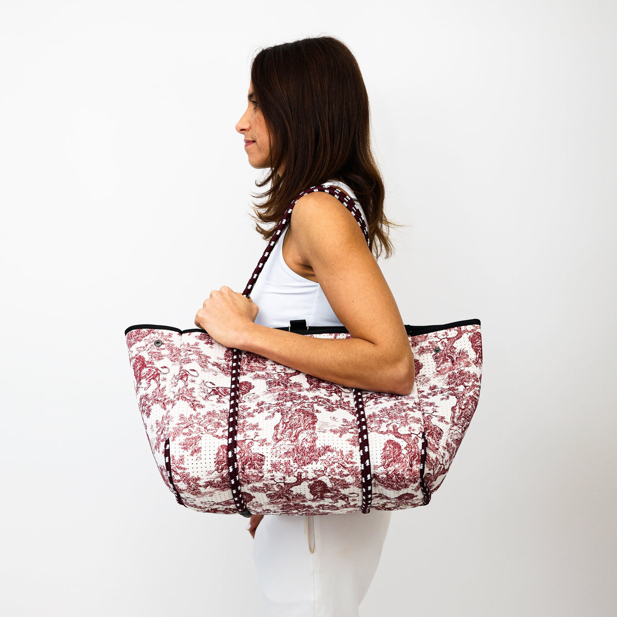 Red-and-white lion print tote bag with black double handles, carried by hand