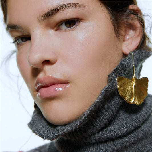 Gold leaf drop hook earrings on model, textured gold leaf drop design