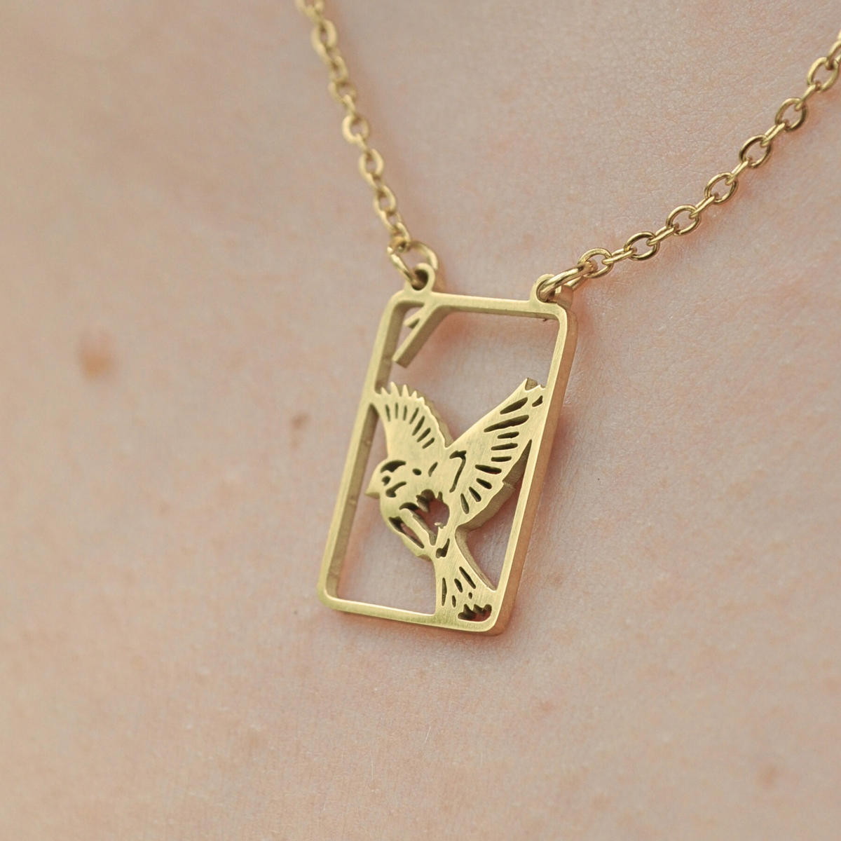 Gold square pendant necklace with bird silhouette in filigree frame
