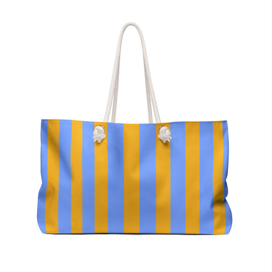 Striped beach tote with rope handles and white pom-pom charms, blue and yellow