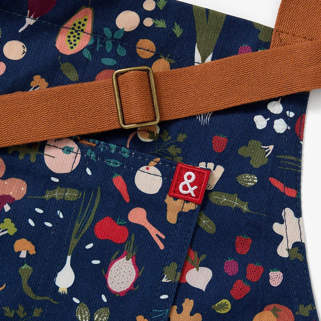Orange-brown neck strap with metal buckle and small & label on navy floral apron