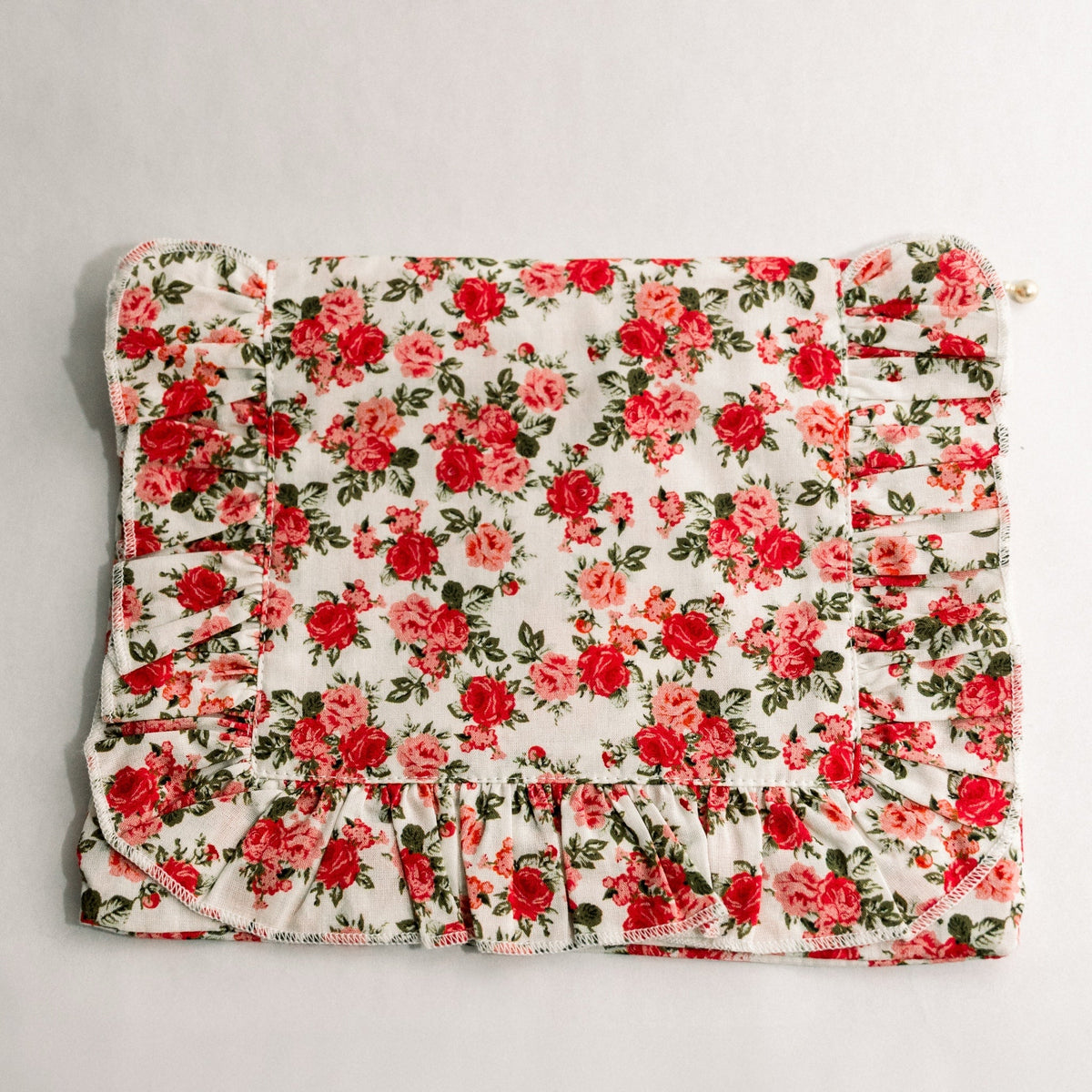Floral ruffle zipper pouch with red rose print, gathered trim, and gold zipper pull