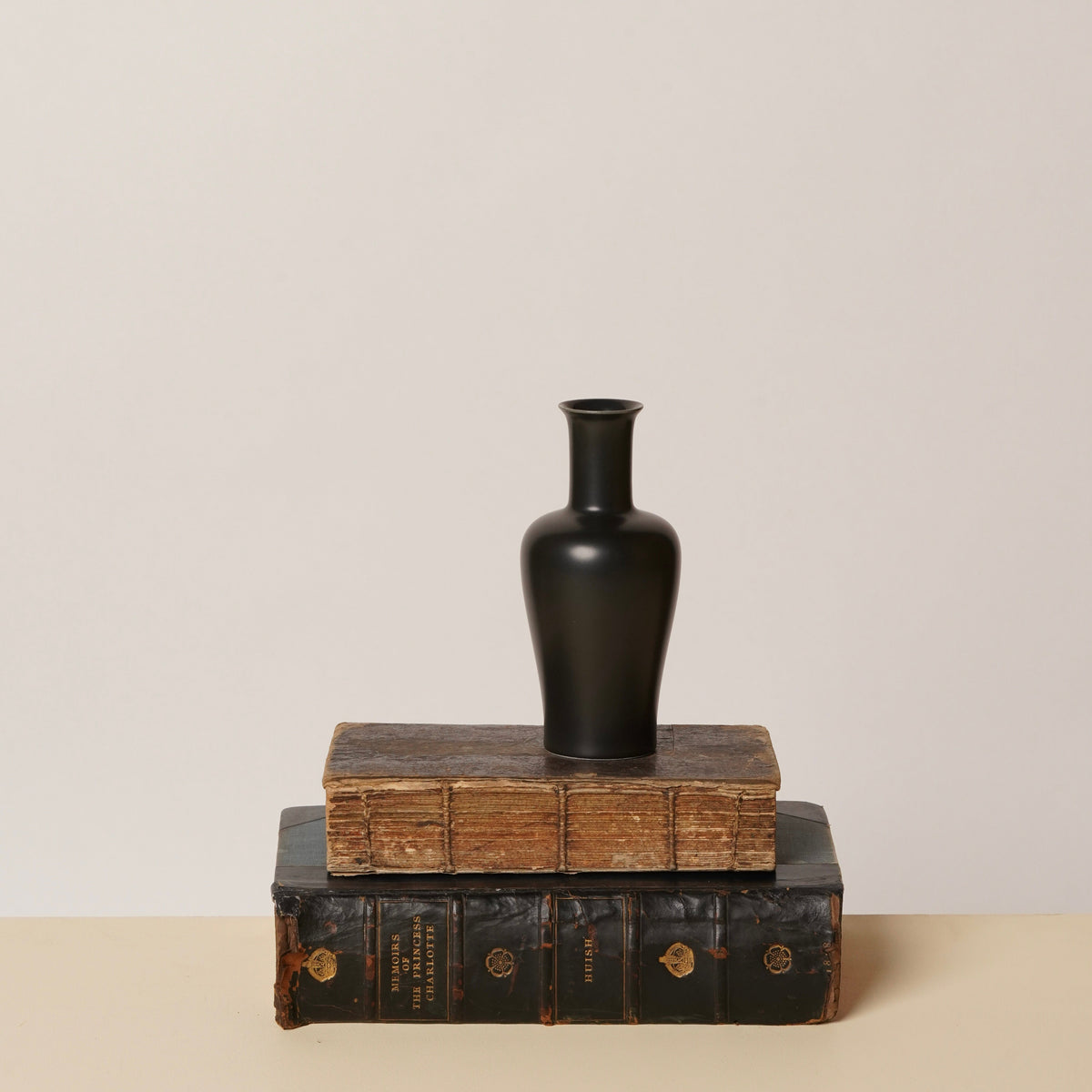 Kirsten vase: black bottle shape on stacked wood and book blocks
