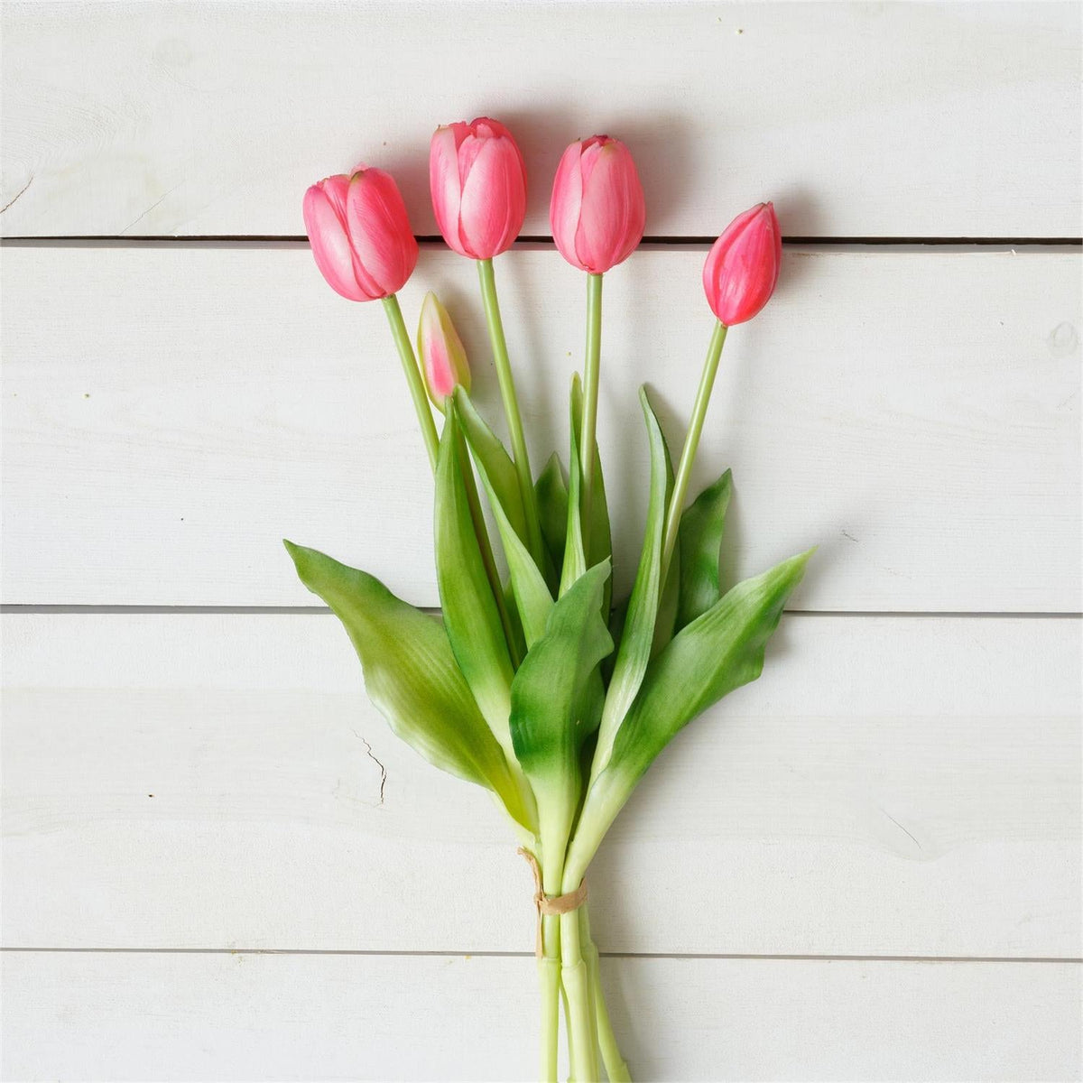 Red-pink tulip bouquet with green stems and leaves