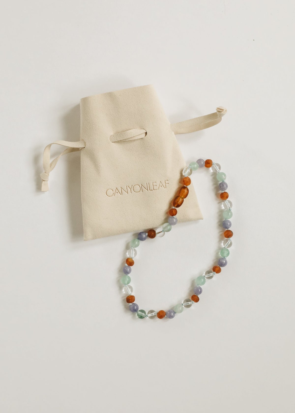 Beaded gemstone necklace with orange amber, mint, and lilac beads with drawstring pouch