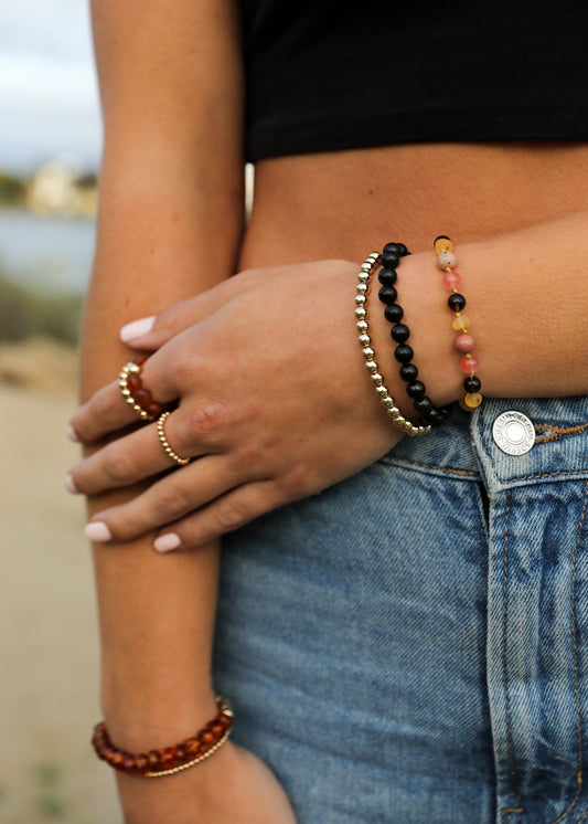 Black shungite beaded bracelet with amber-toned center beads worn on wrist