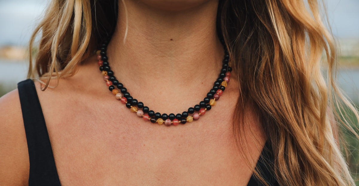 Black shungite beaded strand with amber-toned center beads on neckline
