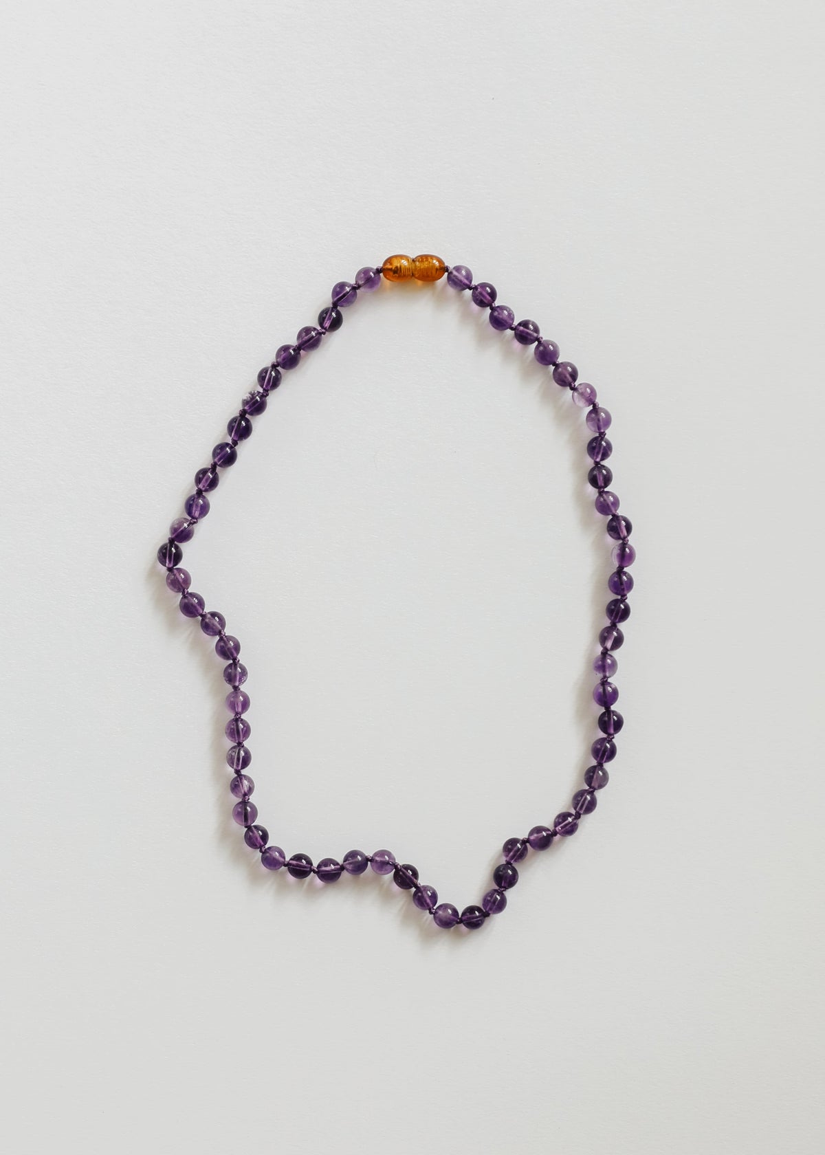 Amethyst bead necklace with purple faceted beads and amber accent at the top