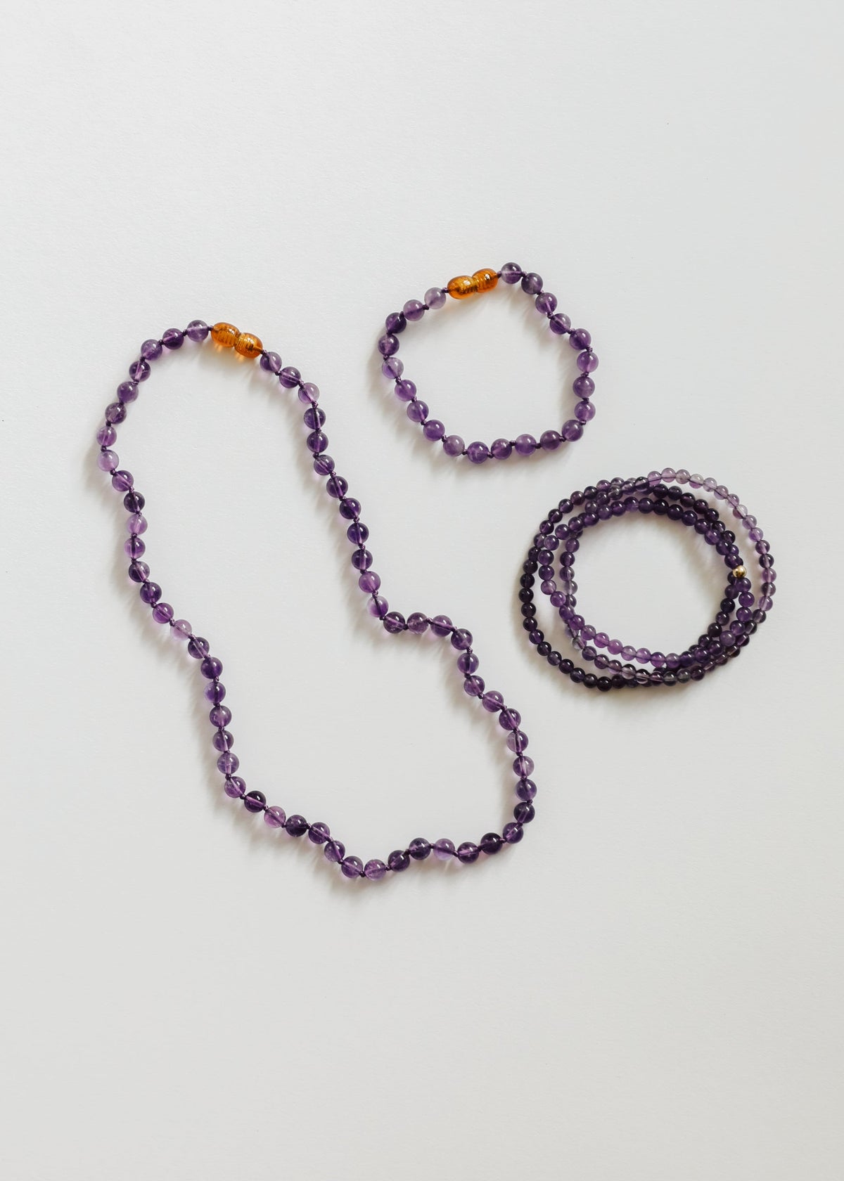 Amethyst bead jewelry set with purple beads and amber accents: necklace and bracelets