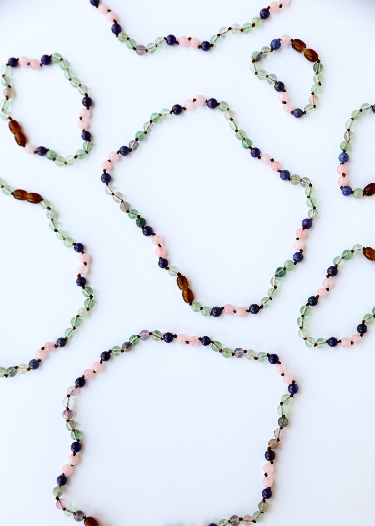 Gemstone bead necklace with green, pink, blue, and amber beads in oval strand