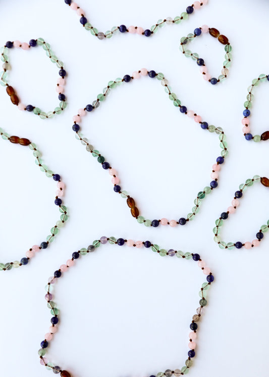 Gemstone bead necklace with green, pink, blue, and amber beads in oval strand