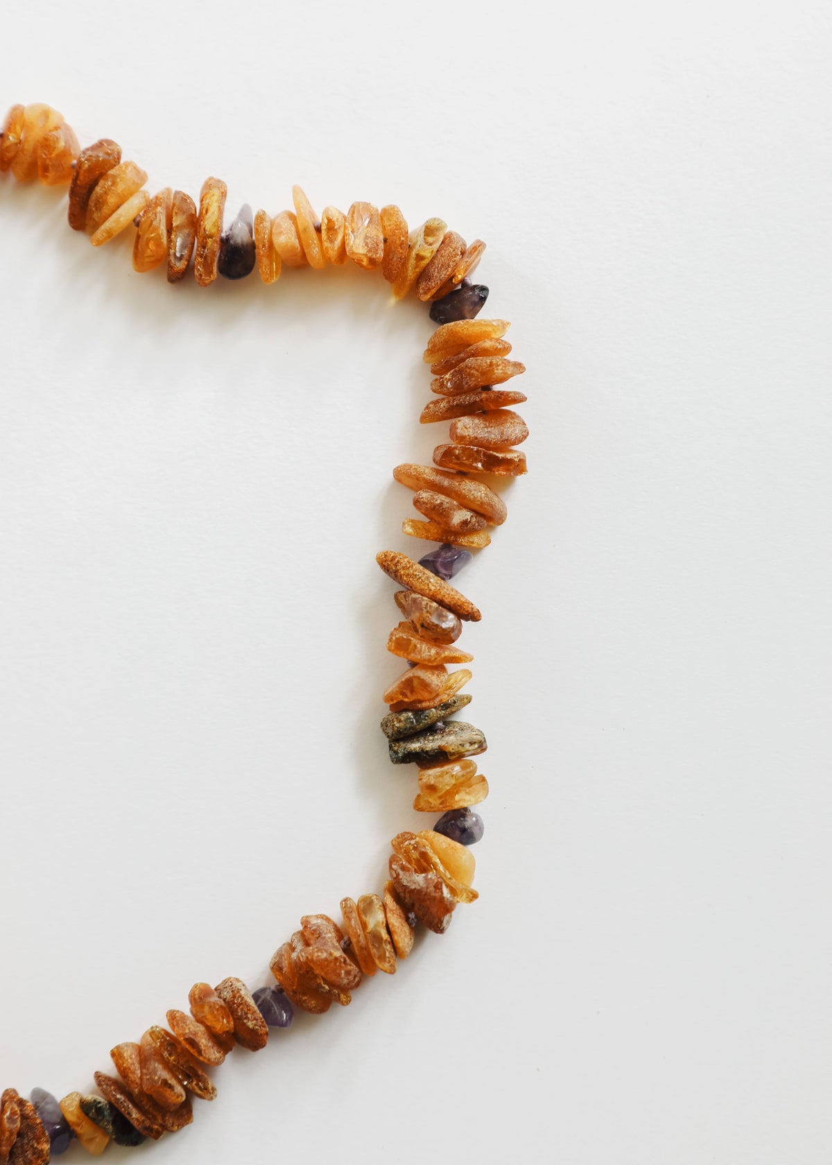 Raw amber and amethyst pet necklace closeup, orange chips with dark purple rough beads