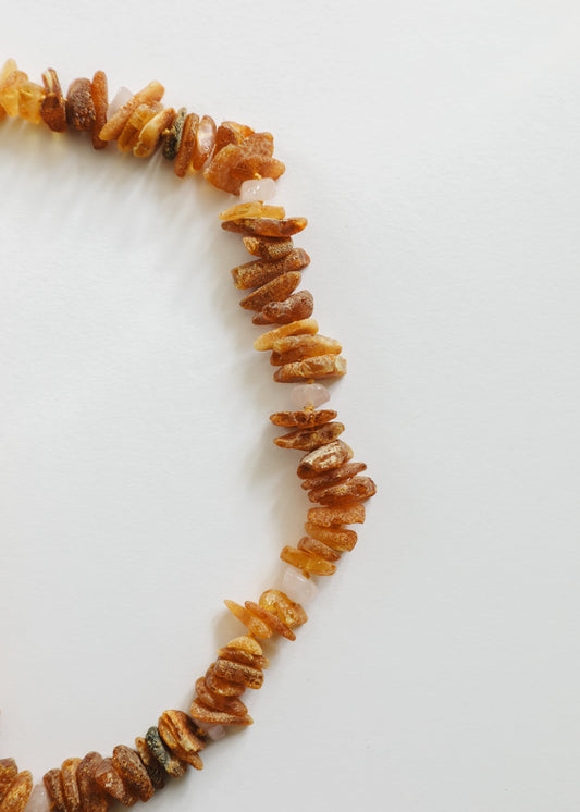Raw amber and rose quartz pet necklace detail, orange stone chips and pale pink pieces