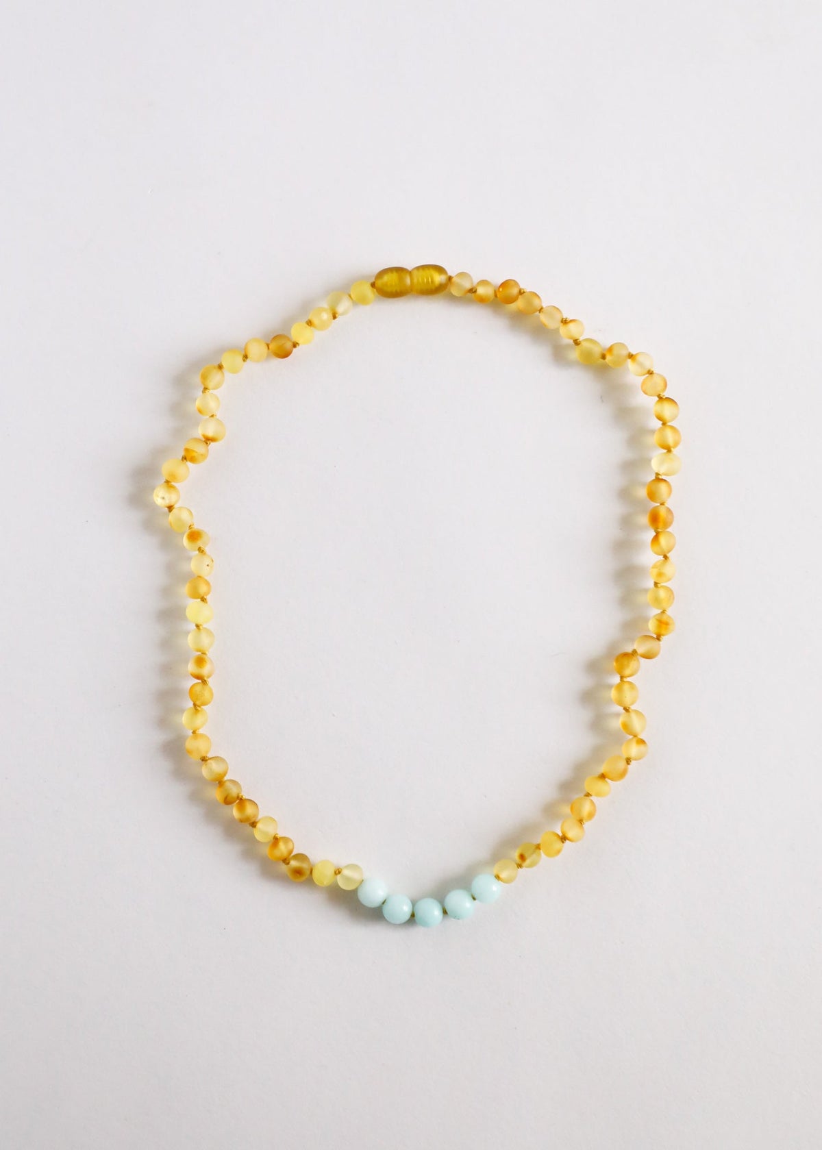 Gold beaded necklace with light blue beads at the bottom, simple round strand