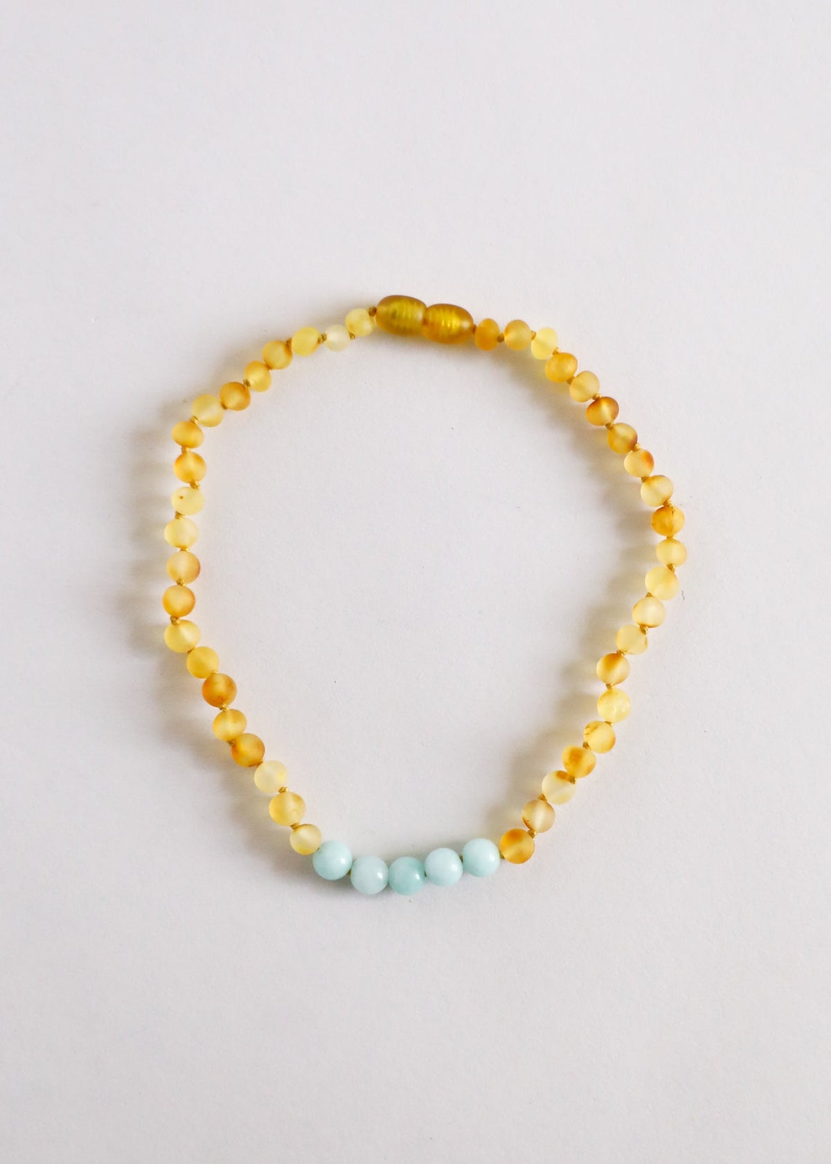 Gold-toned beaded necklace with light blue accent beads in a teardrop strand