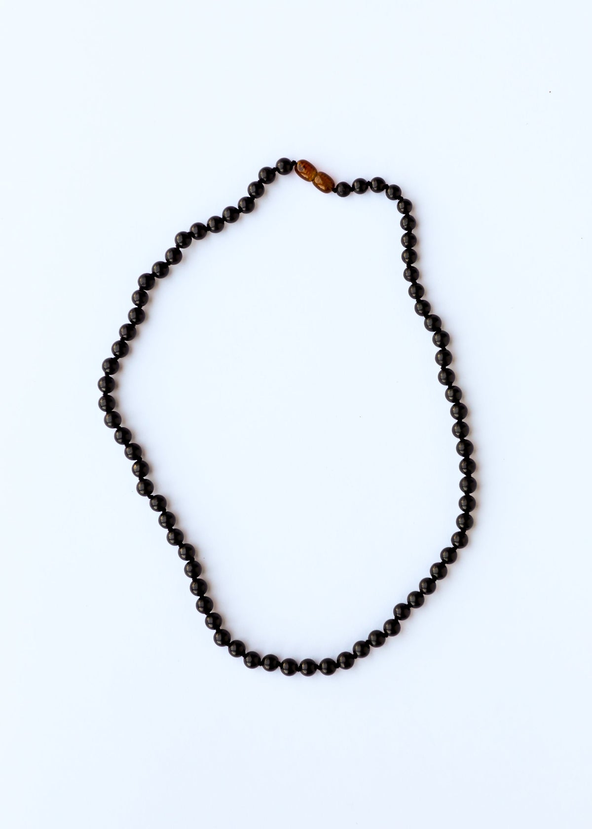 Black shungite beaded bracelet or anklet with amber-toned bead near the top