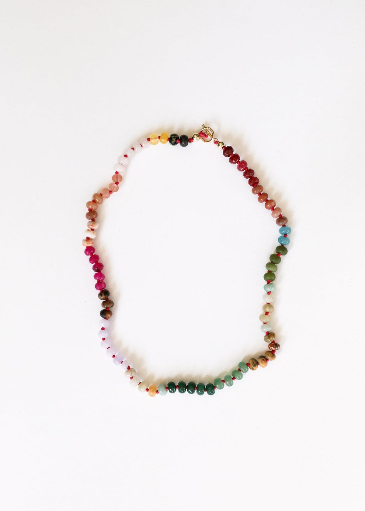 Multi-color gemstone beaded necklace with small gold toggle clasp, shown laid out.