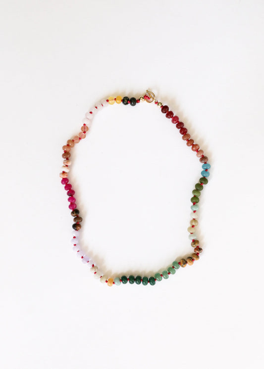 Multi-color gemstone beaded necklace with small gold toggle clasp, shown laid out.