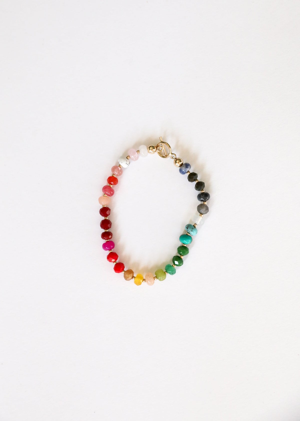 Rainbow gemstone beaded bracelet with circular gold-tone charm and toggle clasp