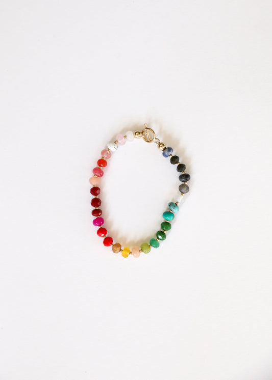 Rainbow gemstone beaded bracelet with circular gold-tone charm and toggle clasp