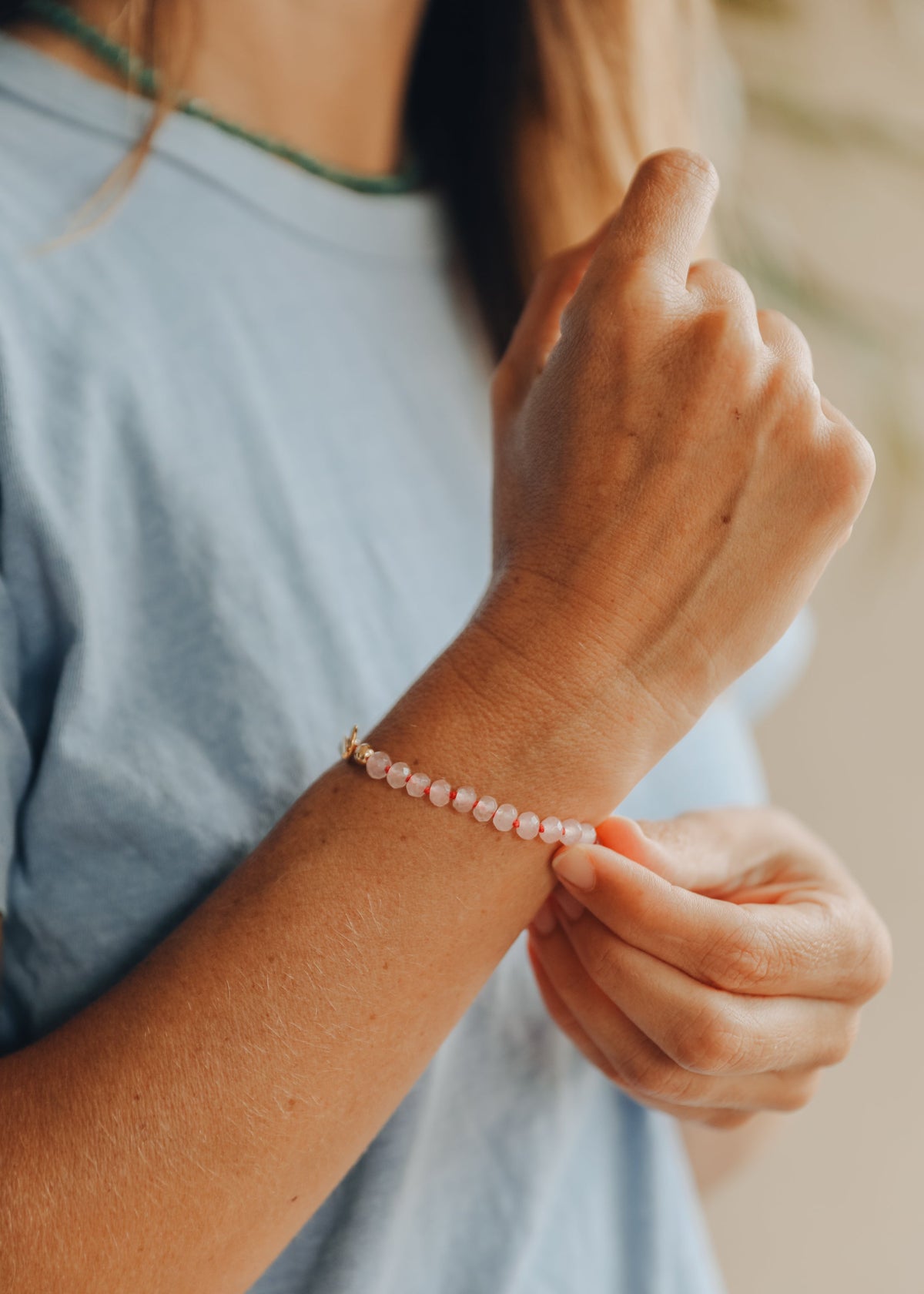 Pink beaded gemstone bracelet on wrist with gold toggle clasp