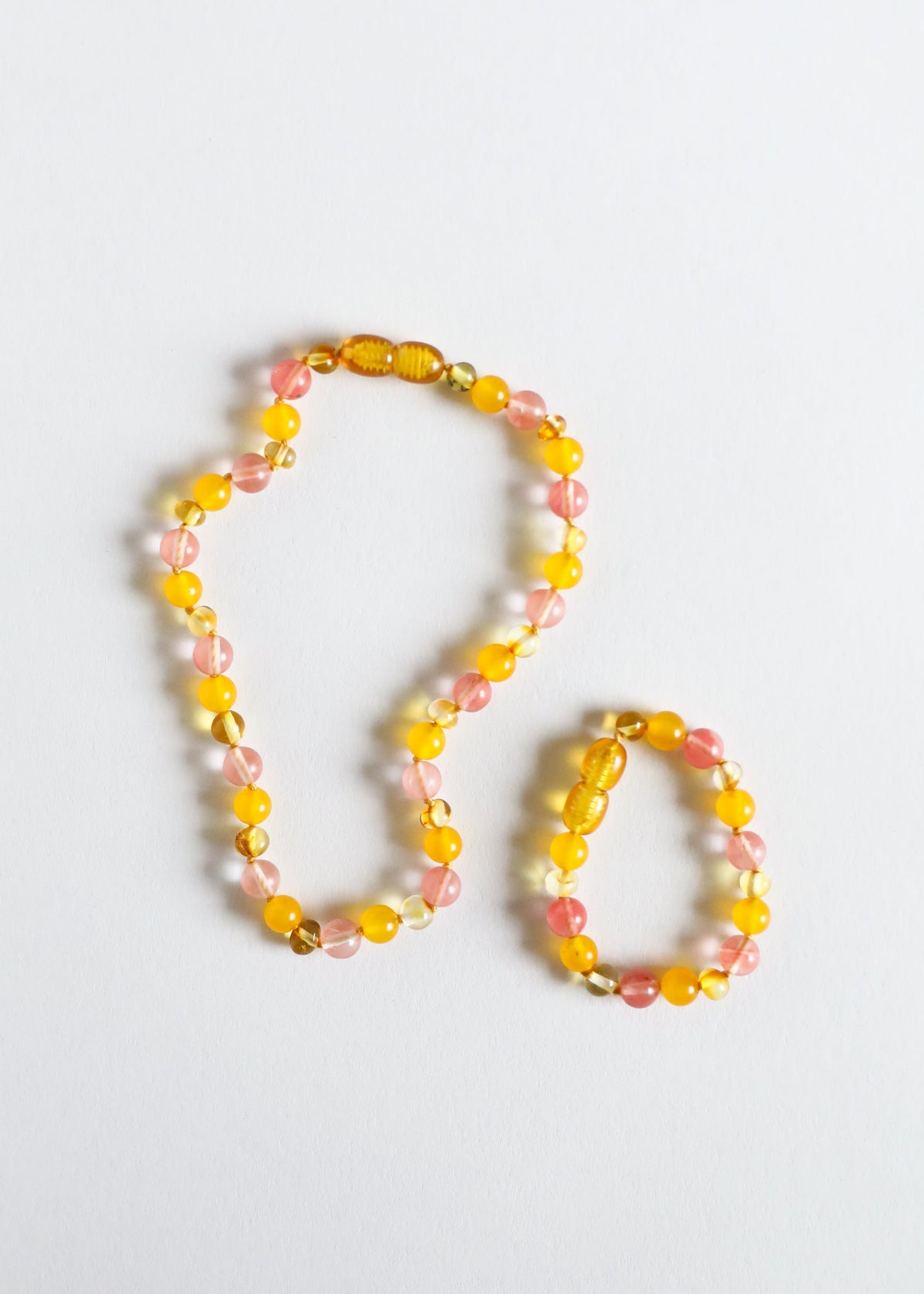 Two beaded amber and pink bracelets/anklets with round beads and gold-toned spacers