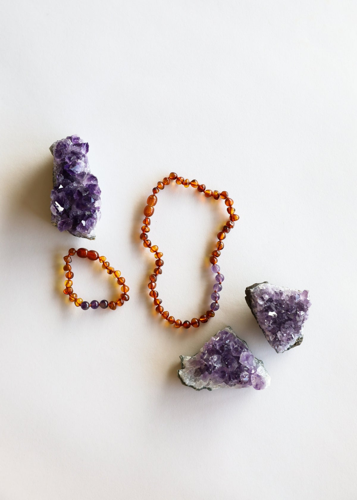 Amber bead necklace with purple amethyst clusters and stones, laid flat
