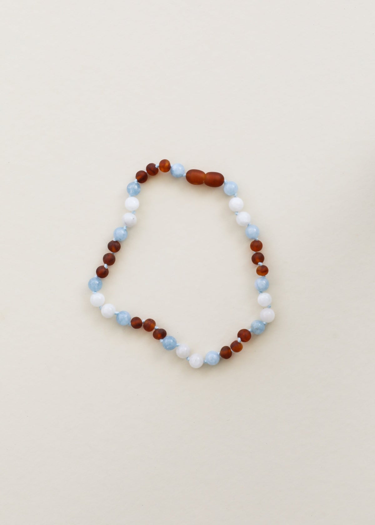 Beaded gemstone necklace with alternating white, light blue and dark amber-brown beads