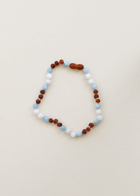 Beaded gemstone necklace with alternating white, light blue and dark amber-brown beads