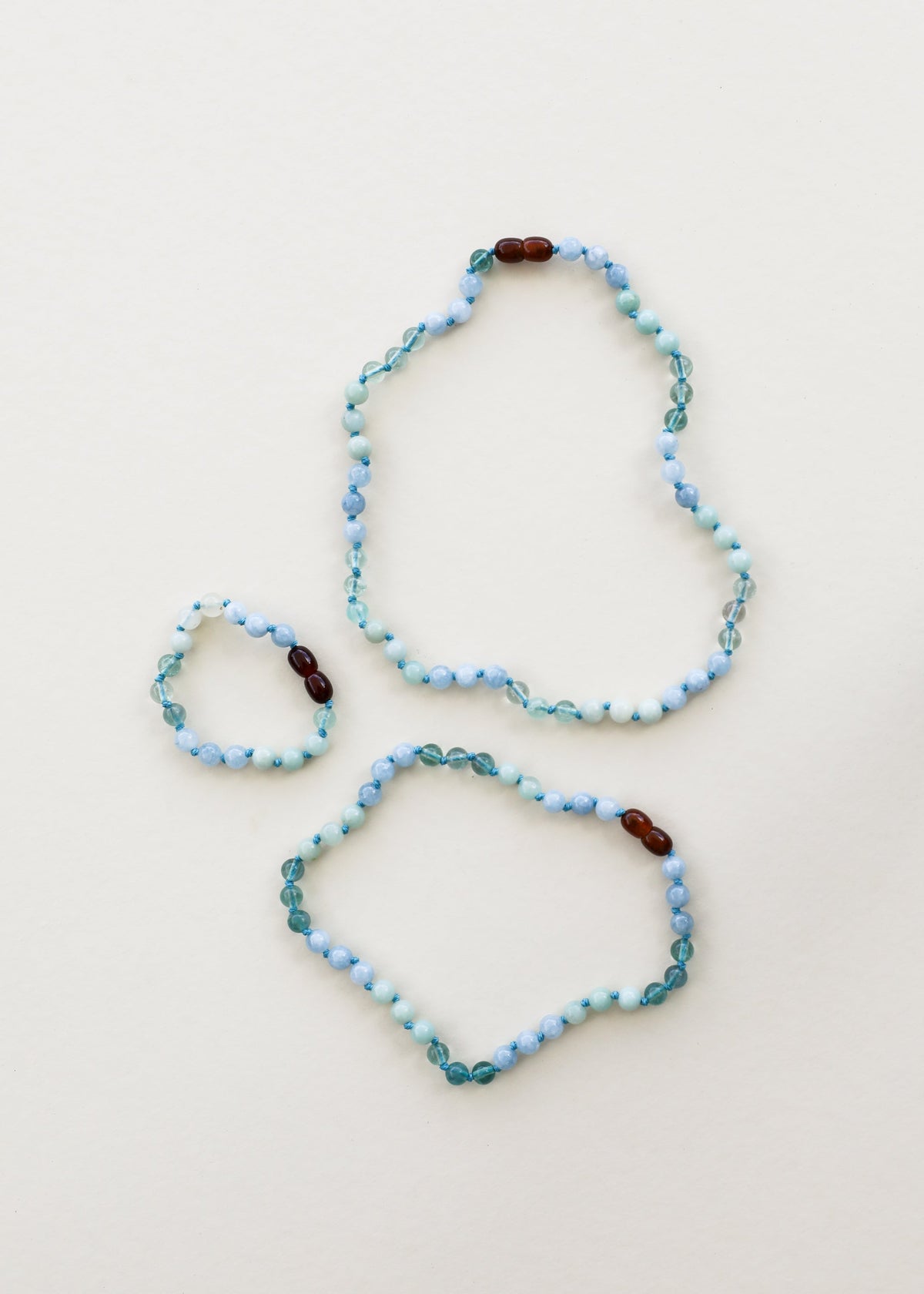 Two light blue gemstone beaded bracelets with dark brown accent beads
