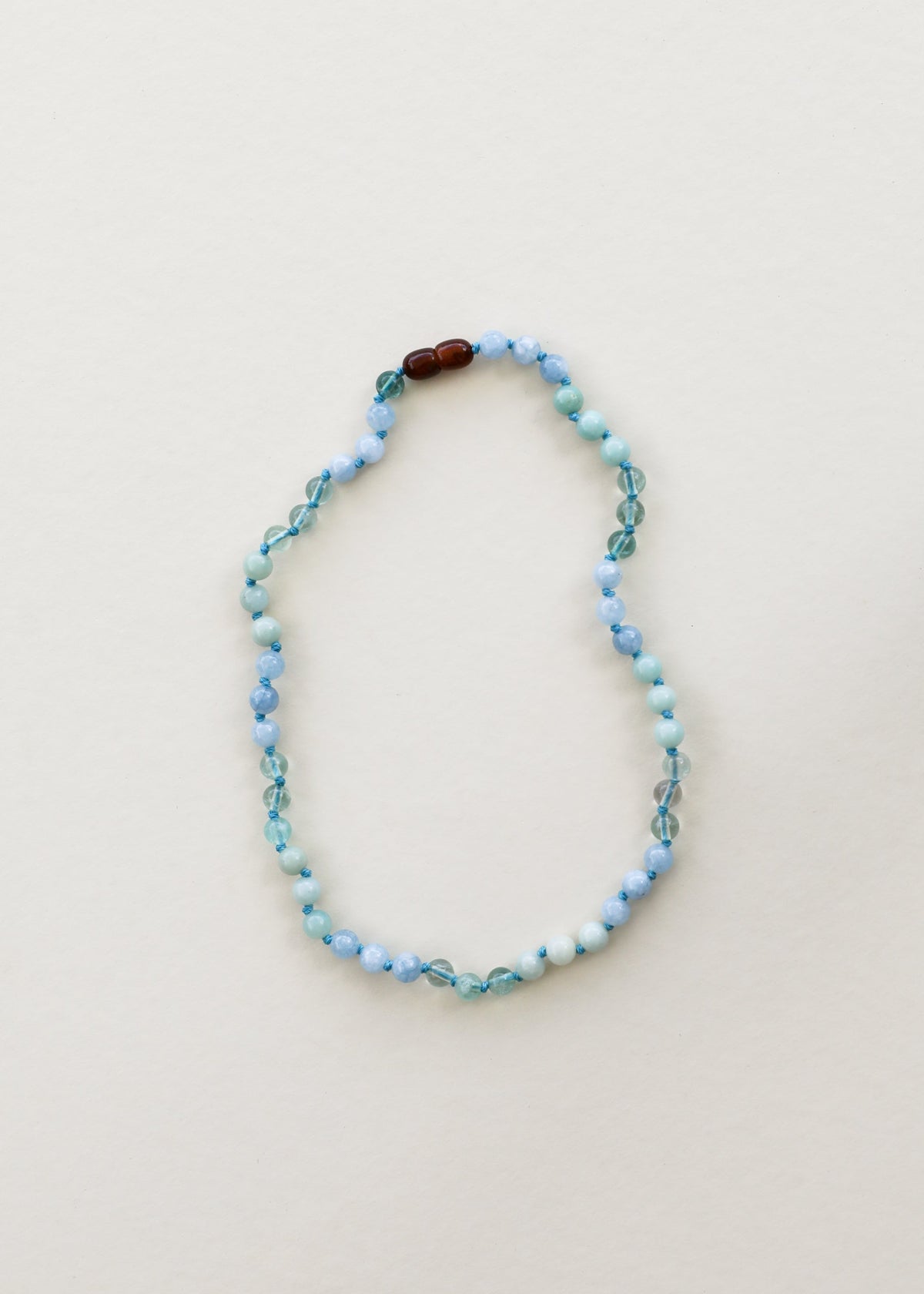 Gemstone bead necklace with light blue beads, teal beads, and dark brown accent